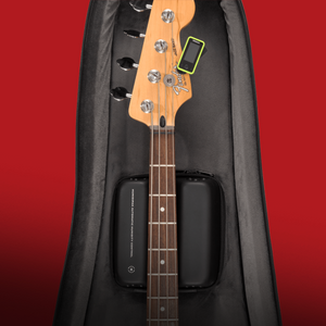 Electric bass guitar with a tuner in a black case on a red background